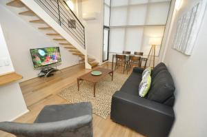 a living room with a black leather couch and a television at Darlinghurst Fully Self Contained Modern 1 Bed Apartment (POP) in Sydney