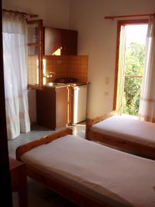 a bedroom with two beds and a kitchen with a window at Eleni Studios & Apartments in Mithymna +17 photos