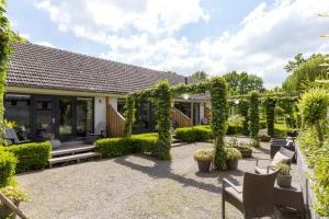 a garden with an arbor and chairs and a house at Rosa Arvensis in Lottum