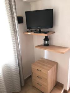 a television on a wall with a wooden shelf at Casa al Castello in Isola del Giglio