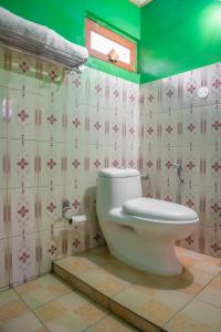 a bathroom with a toilet and a green wall at The Monk Campsite by Livingstone in Kalpa