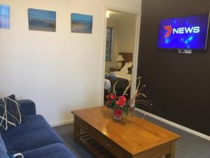 a living room filled with furniture and a tv at Anchor Belle Motel in Warrnambool
