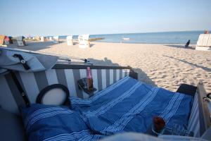 um banco na praia ao lado da praia em Schlafstrandkorb Nr. 1 em Sierksdorf