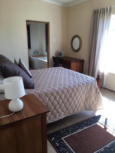 1 dormitorio con 1 cama y 1 mesa con lámpara en Forget-Me-Not Cottage, en Krugersdorp