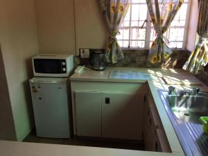 a small kitchen with a microwave on top of a refrigerator at Forget-Me-Not Cottage in Krugersdorp