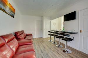 a living room with a leather couch and bar stools at Thistledew in Hunstanton