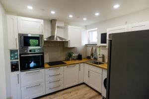 a kitchen with white cabinets and a black refrigerator at Ferienwohnung Essen - Zentral im Ruhrgebiet in Essen +5 photos