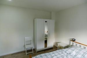 a bedroom with a white cabinet and a chair at Ferienwohnung Essen - Zentral im Ruhrgebiet in Essen
