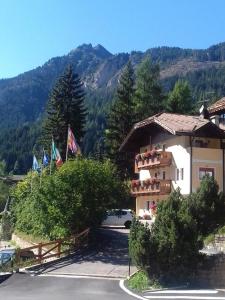 un edificio con banderas frente a una montaña en Appartamenti Riz Claudio, en Campitello di Fassa