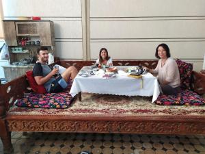 eine Gruppe von drei Personen, die um einen Tisch sitzen in der Unterkunft Uvaysiy family guest house in Margilan
