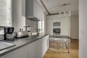 a kitchen with white cabinets and a table with chairs at Design Apt 4 pers - Paris 8ème in Paris