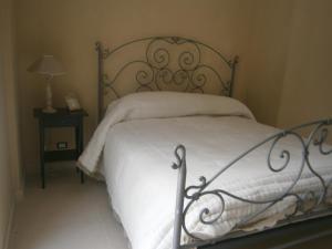 a bed with white sheets and a metal frame at Residenza Don Agostino in Vallo della Lucania