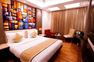a bedroom with a large bed with a painting on the wall at Hotel City Pride in New Delhi