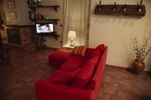 a living room with a red couch and a tv at ALLEGRETTI'S HOUSE VENOSA, ospitalità e accoglienza in Venosa