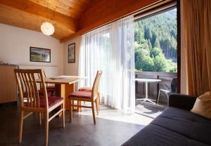 een woonkamer met een tafel en stoelen en een groot raam bij Haus 4 Montafon by Pferd auf Wolke in Gaschurn