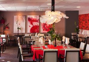 a dining room with tables and chairs and a chandelier at Ax Hôtel Spa & Restaurant in Chorges