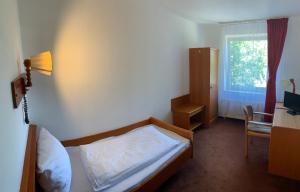 a bedroom with a bed and a desk and a window at Hotel Rahlstedter Hof in Hamburg