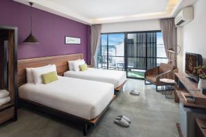 Amphawa Nanon Hotel في أمفاوا: غرفة فندقية بسريرين وبلكونة