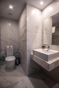 a white bathroom with a sink and a toilet at Narcissos Waterpark Resort in Protaras