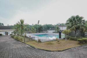 a swimming pool with palm trees in front of a building at RedDoorz Premium @ Jalan Pal 10 Jambi in Jambi