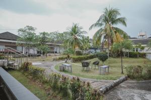 a view of a park with tables and palm trees at RedDoorz Premium @ Jalan Pal 10 Jambi in Jambi