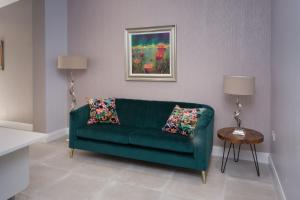 a green couch in a living room with a painting at Titanic Guest Boutique, 4-Star Accommodation in Belfast