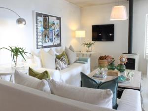 uma sala de estar com sofás brancos e uma televisão em Village Square 10 em Plettenberg Bay