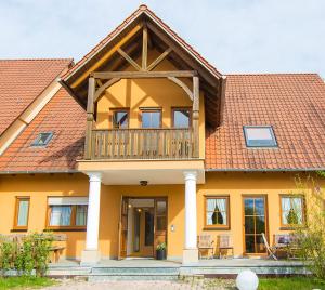 a house with a balcony on top of it at Steigerwaldpension in Wiesentheid