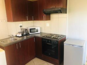 a small kitchen with a stove and a microwave at A Contempo Guesthouse in Bloemfontein