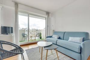 a living room with a blue couch and a table and chairs at Luminous Apt 4pers with balcony in Paris