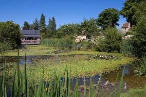 einen Teich in einem Garten mit einem Haus im Hintergrund in der Unterkunft La Ferme de l'Oudon & SPA in Berville