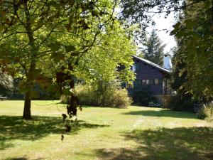 a house with a yard with a tree and a dog at Luxury Pet friendly Chalet in Bi vre near Forest in Bièvre