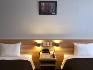 ein Hotelzimmer mit 2 Betten und einem Telefon auf dem Tisch in der Unterkunft Izumisano Center Hotel Kansai International Airport in Izumi-Sano