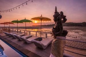 a statue on a dock with chairs and umbrellas on the beach at Rumah Marta Ceningan Island in Nusa Lembongan