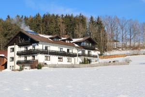 een groot wit huis in de sneeuw met bomen bij Gästehaus Penzkofer F**** in Viechtach