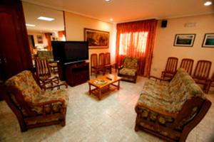 a living room with chairs and a flat screen tv at Hotel Lusitano in Lobios