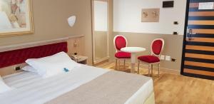 a bedroom with a bed and two red chairs at Santa Barbara Hotel in San Donato Milanese