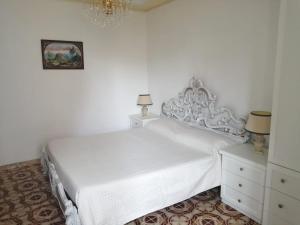 Habitación blanca con cama blanca y lámpara de araña. en Antico Borgo, en Bagnoregio