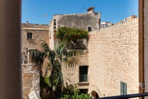 um edifício de pedra com uma palmeira em frente em ARA Alcudia na Alcúdia