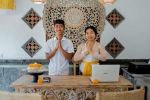 a man and a woman are performing a meditation gesture at Santosha Place in Ubud