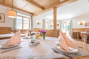 ein Esszimmer mit einem Tisch mit Tellern und Küchenutensilien in der Unterkunft Hotel Garni Gästehaus Brand in Bad Wiessee