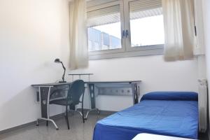 1 dormitorio con cama, escritorio, cama y ventana en Residencia Universitaria Resa Campus de Montilivi, en Girona