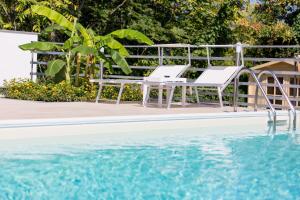 a pair of white chairs next to a swimming pool at Veda elegant rooms in Fiumefreddo di Sicilia