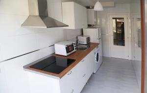 a white kitchen with a stove and a microwave at Apartamento puente romano P2 1G in Salamanca
