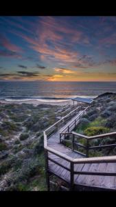 a wooden boardwalk leading to the ocean at sunset at Telperio - Guest suite max 4 Guests in Bunbury