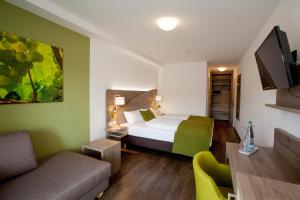 um quarto de hotel com uma cama e um sofá em Wein & Bett Weihbrecht em Bretzfeld