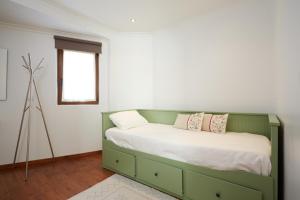 a bedroom with a green bed with two pillows at Casa Nascente - Água Formosa _ Vila de Rei in Vila de Rei