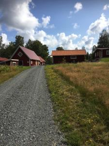 un camino de grava junto a un granero y un campo en Smålandstorpet en Hok