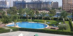 uma vista sobre uma piscina com palmeiras e edifícios em Apartamento en residencial arenas San Juan em Alicante