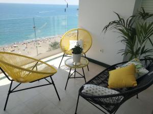 a living room with chairs and a balcony with the ocean at MALAGUETA BEACH in Málaga